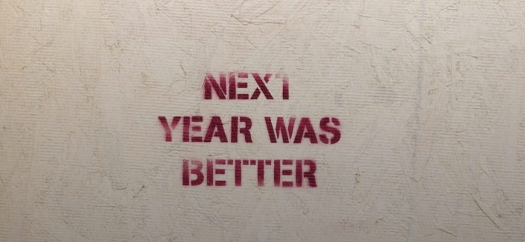 This image shows a whitish piece of paper and on it, there are stamped 4 words in red ink- “Next year was better”